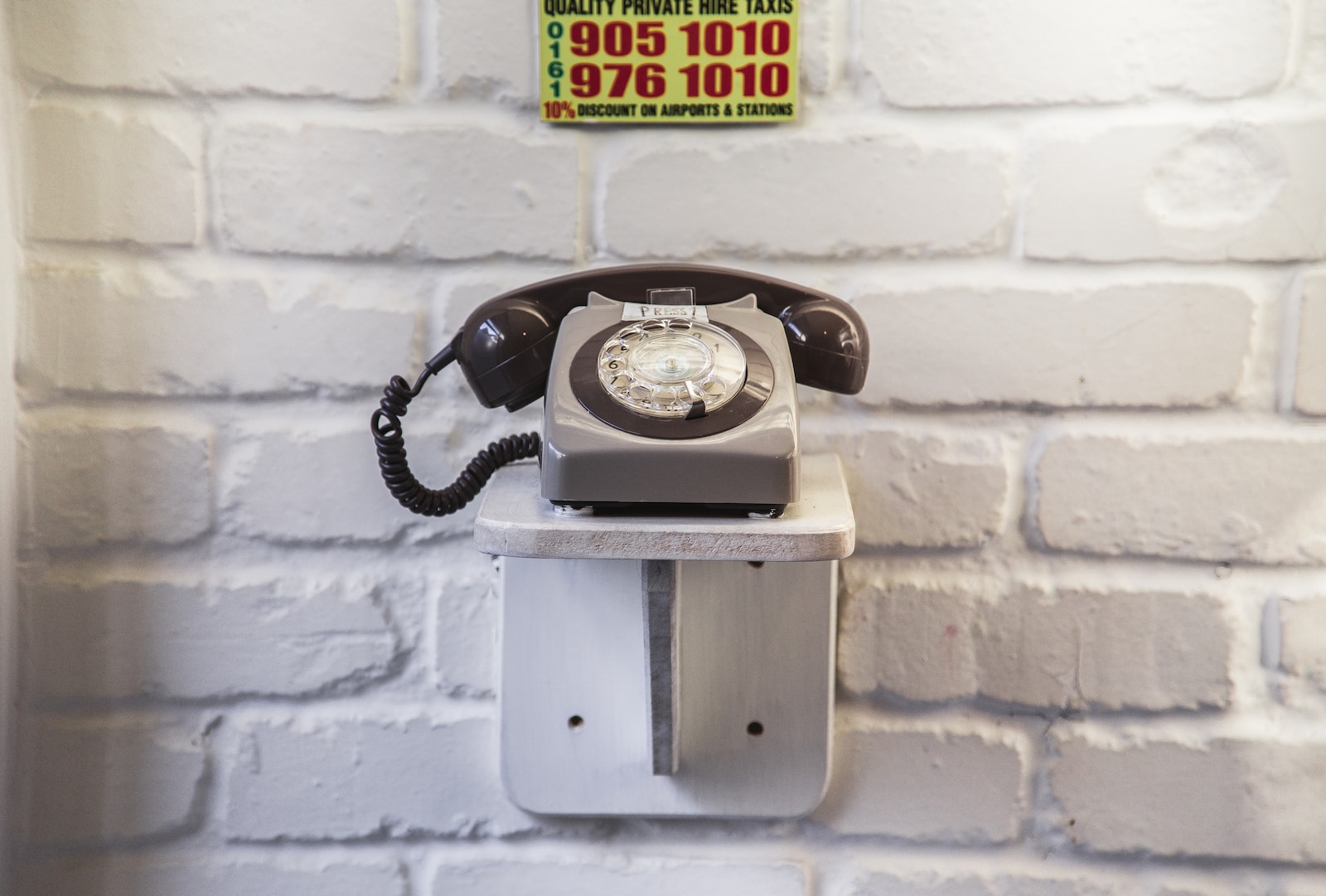 an old fashioned telephone on a wall in front of a brick wall